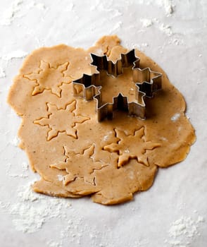 Making gingerbread cookies for Christmas. Gingerbread dough with star shapes and a cutter.