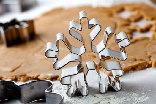 Making gingerbread cookies for Christmas. Gingerbread dough with star shapes and a snowflake cutter.