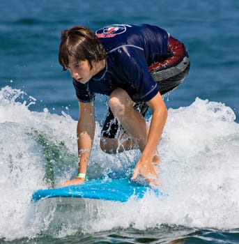 A teenager surfing. The boy is just beginning to stand up on the surfboard.
