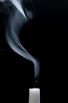 A white candle smokes after blowing out