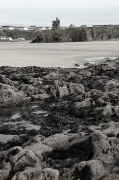 a rocky beach with castle on a warm day with a calm sea an ideal place to have a walk in ireland