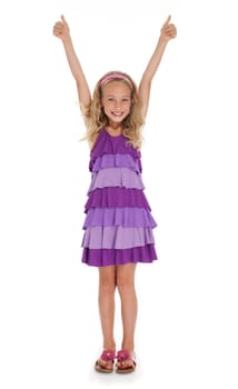 Pretty seven year old girl with arms extended overhead giving thumbs up gesture on white background.