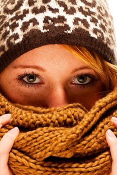 Young woman with freckles hiding behind winter clothes