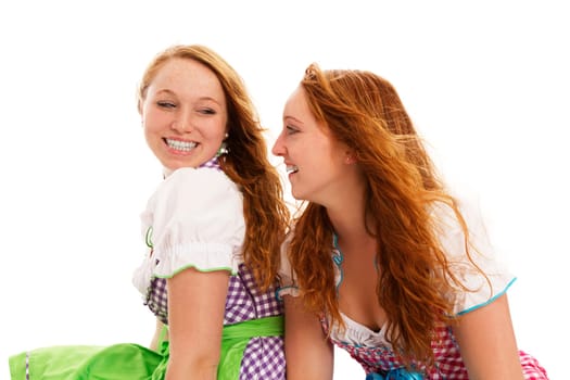 Two women in dirndls looking at each other on white background