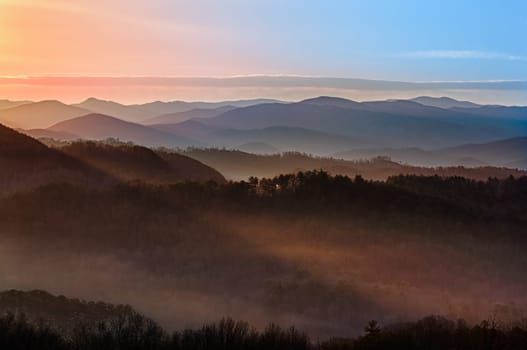 Sun rising over snowy mountains of Smokies in early spring with fog in valleys
