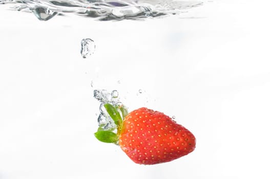 Studio shot of strawberry falling into water on white background