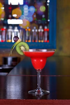 red cocktail with kiwi on the wooden bar