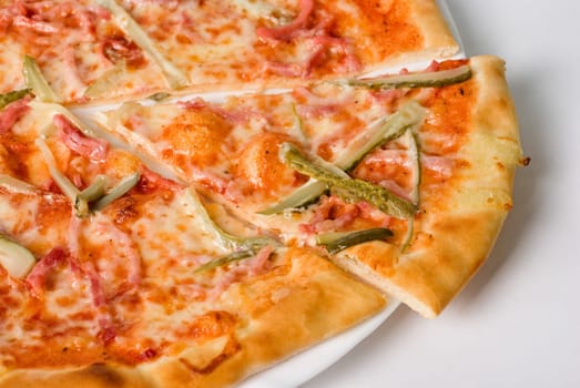 pizza closeup with boiled sausage, ham, marinated gherkin and mozzarella cheese