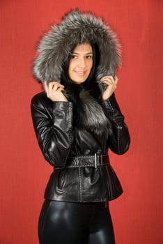beautiful woman in a fur coat on a red background