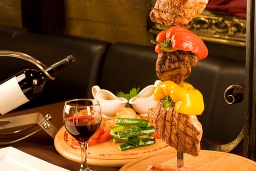 Big tasty roasted meat cuts at skewer on a decorated table