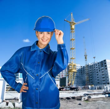 Builder pretty girl at helmet on a building background