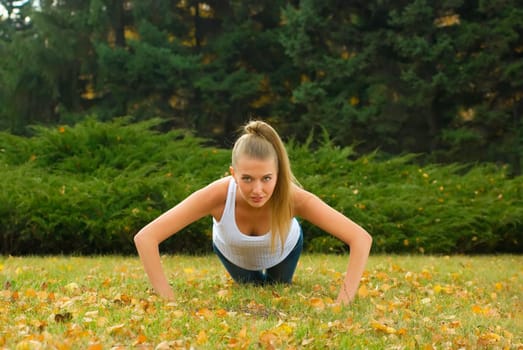 Beauty female doing push ups in the park