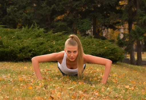 Beauty female doing push ups in the park
