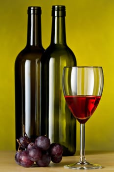 Grapes with red wine and a bottle of wine with yellow background