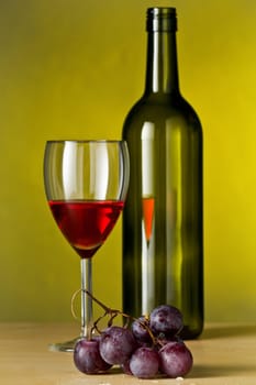 Grapes with red wine and a bottle of wine with yellow background