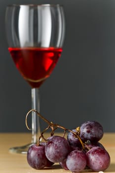 Grapes with red wine and a bottle of wine with gray background