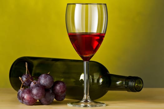 Grapes with red wine and a bottle of wine with yellow background