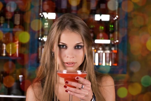 Beauty young woman portrait with a glass drinking a cocktail at a bar