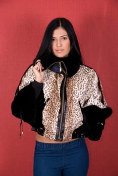 beautiful woman in a leopard jacket on a red background