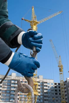 man hands closeup with crane hook at building background