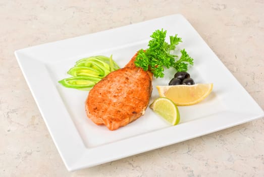 Grilled salmon steak with greens,onion, lemon, lime and olive