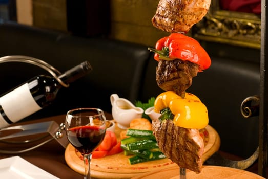 Big tasty roasted meat cuts at skewer on a decorated table