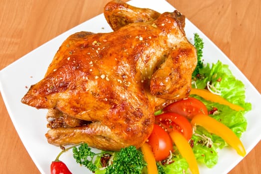 roasted chicken garnished with fresh tomatoes, green salad, pepper and greens