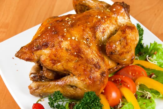 roasted chicken garnished with fresh tomatoes, green salad, pepper and greens
