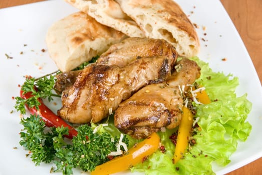 roasted chicken drumstick garnished with fresh green salad, pepper and greens