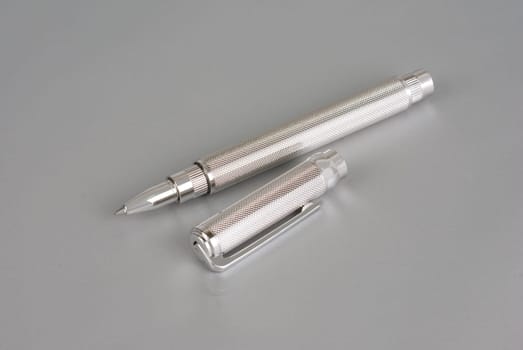 Stylish ballpoint pen of white gold on a grey