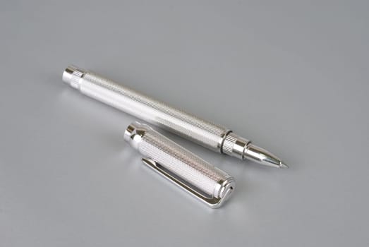 Stylish ballpoint pen of white gold on a grey