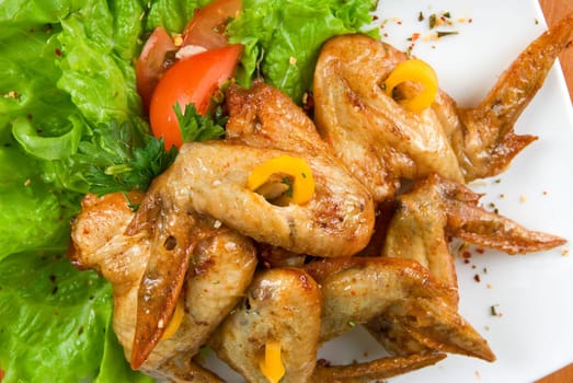 roasted chicken wings garnished with fresh green salad, pepper and greens