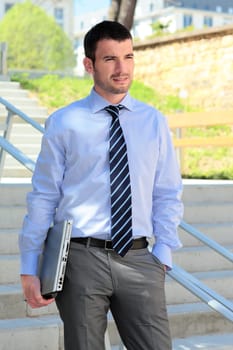 standing businessman waiting outdoor with laptop on stairs