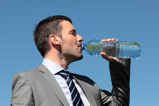 handsome man drinking water in blue sky