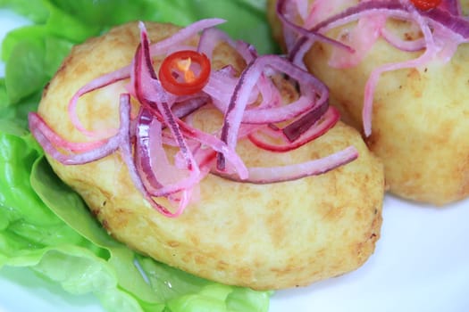 A close up of a papa rellena (a traditional Peruvian stuffed potato dish) on a pale blue plate.