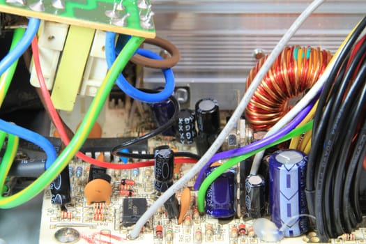 A close up of the circuit board of a computer power supply showing capacitors and resistors.
