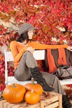 Autumn park young woman relax sitting on bench with pumpkins