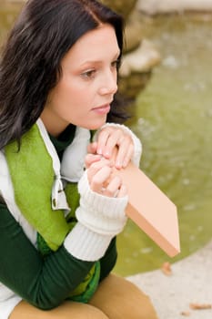 Autumn park young woman reading book sitting on fountain