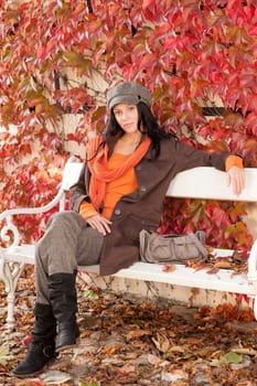 Autumn park scenery young woman relax on bench fashion model