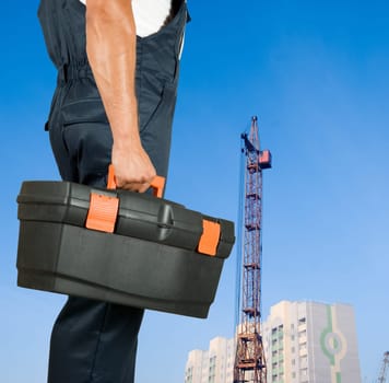 repairman with box of instruments on building background