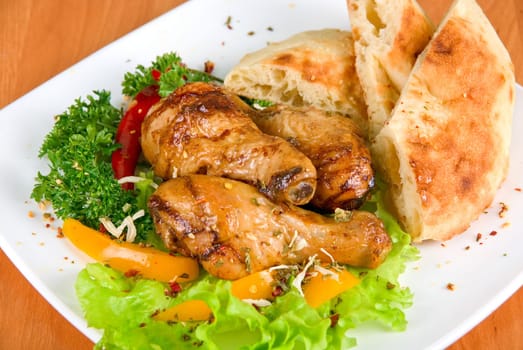 roasted chicken drumstick garnished with fresh green salad, pepper and greens
