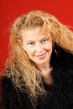 Portrait of a blond woman with blue eyes over a red fabric background
