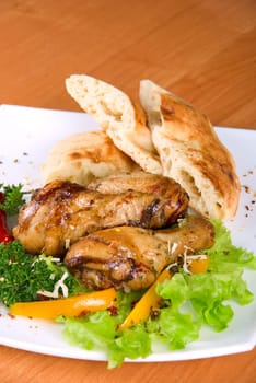 roasted chicken drumstick garnished with fresh green salad, pepper and greens