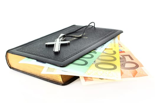 Euronote,hymnal and cross against white background