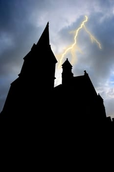 Old silhouetted building with towers and lightning in the background