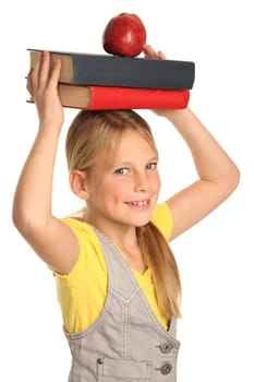 Lovely young school school with pile of books and red apple on her head