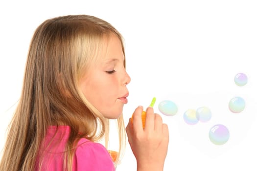 Little girl with blond hair blowing soap bubbles