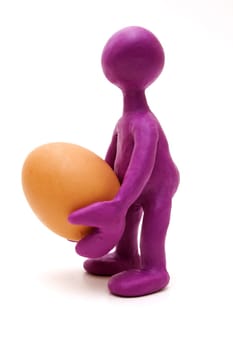 Purple man puppet of plasticine holding one egg