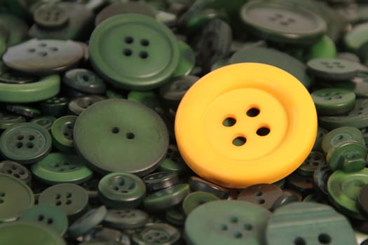 A yellow button on top of a whole lot of green buttons