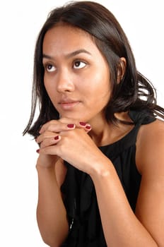 A lovely Asian woman, with her hands under her chin, looking up, in ab lack dress and long brunette hair, for white background.